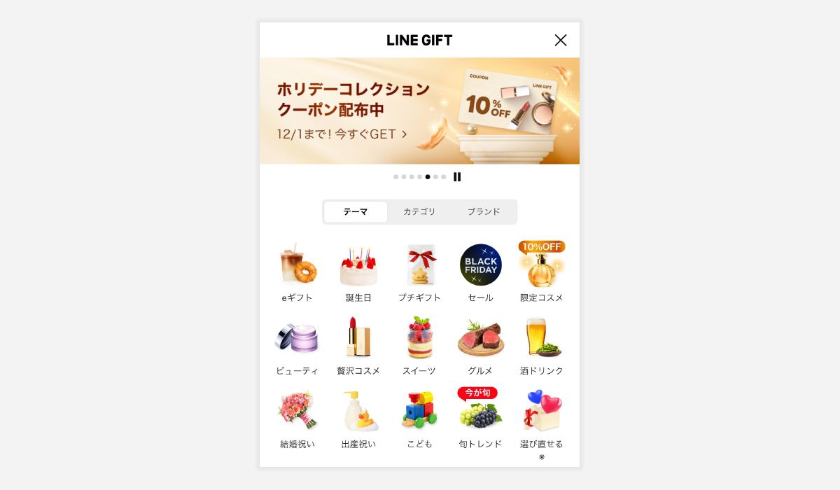 画面上部に「LINE GIFT」と表示され、その下にホリデー向けのクーポン告知バナーがあり、「ホリデーコレクション クーポン配布中」「12/1まで！今すぐGET」と書かれている。10％OFFのクーポンカードとコスメの小物が金色の背景の上に配置され、きらめく演出が施されている。バナー下にはスライドのインジケーターがあり、その下には「テーマ」「カテゴリ」「ブランド」のタブが並ぶ。