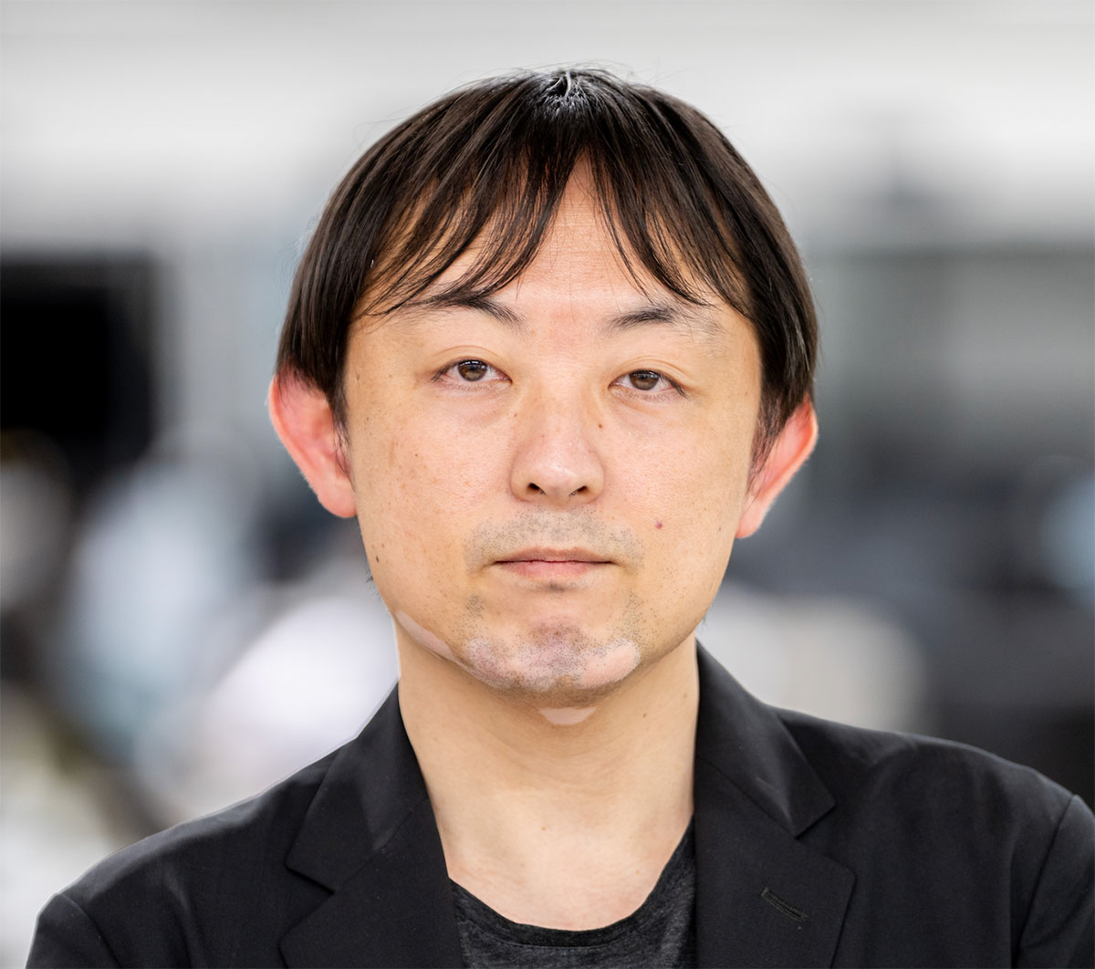 黒のジャケットを着た児玉和也のクローズアップです。真剣な表情でカメラを見つめています。