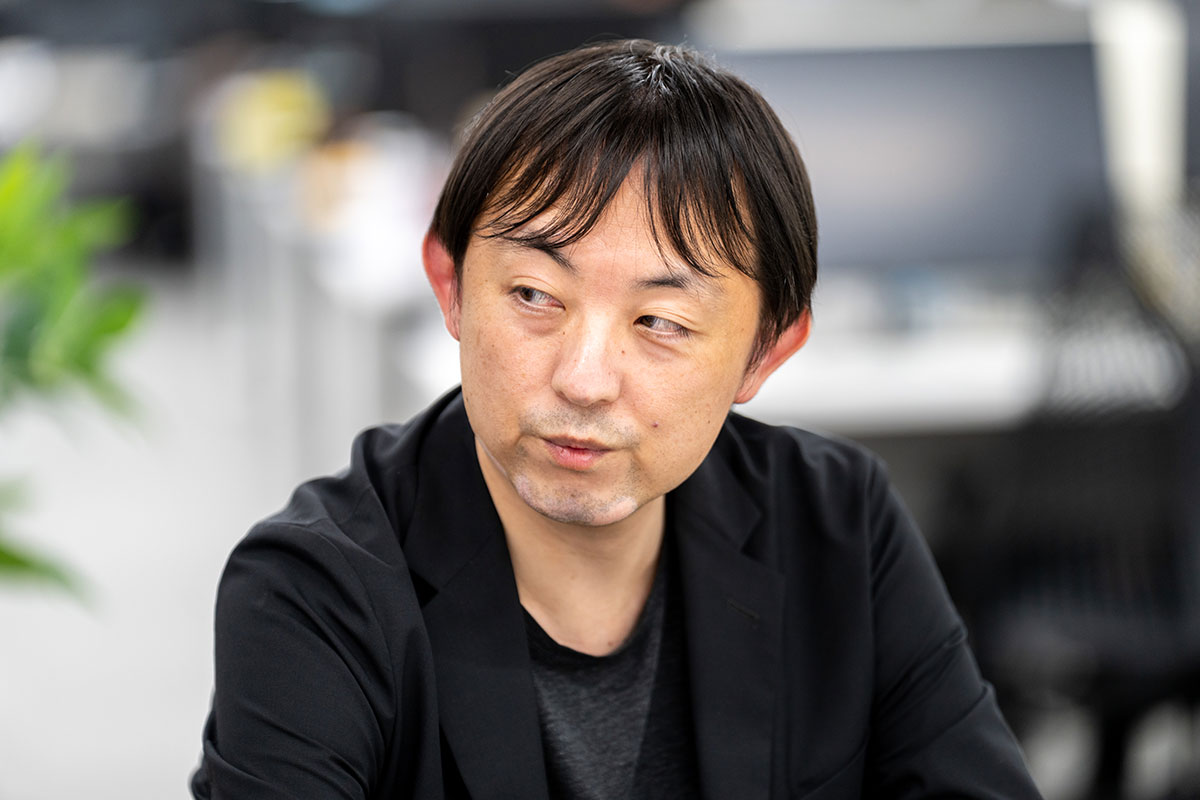 黒のジャケットを着た児玉が考え込むように横を見ている様子を捉えています