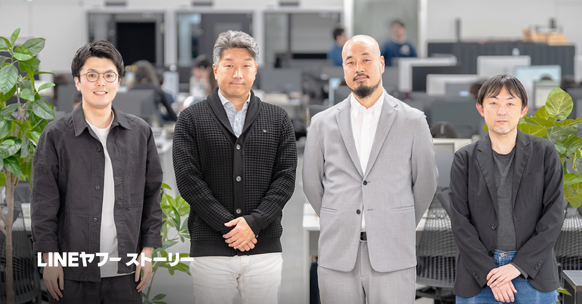 オフィスで並んで立っている4人の男性を写しています。背景にはデスクや植物が見えます。「LINEヤフーストーリー」と書かれています。